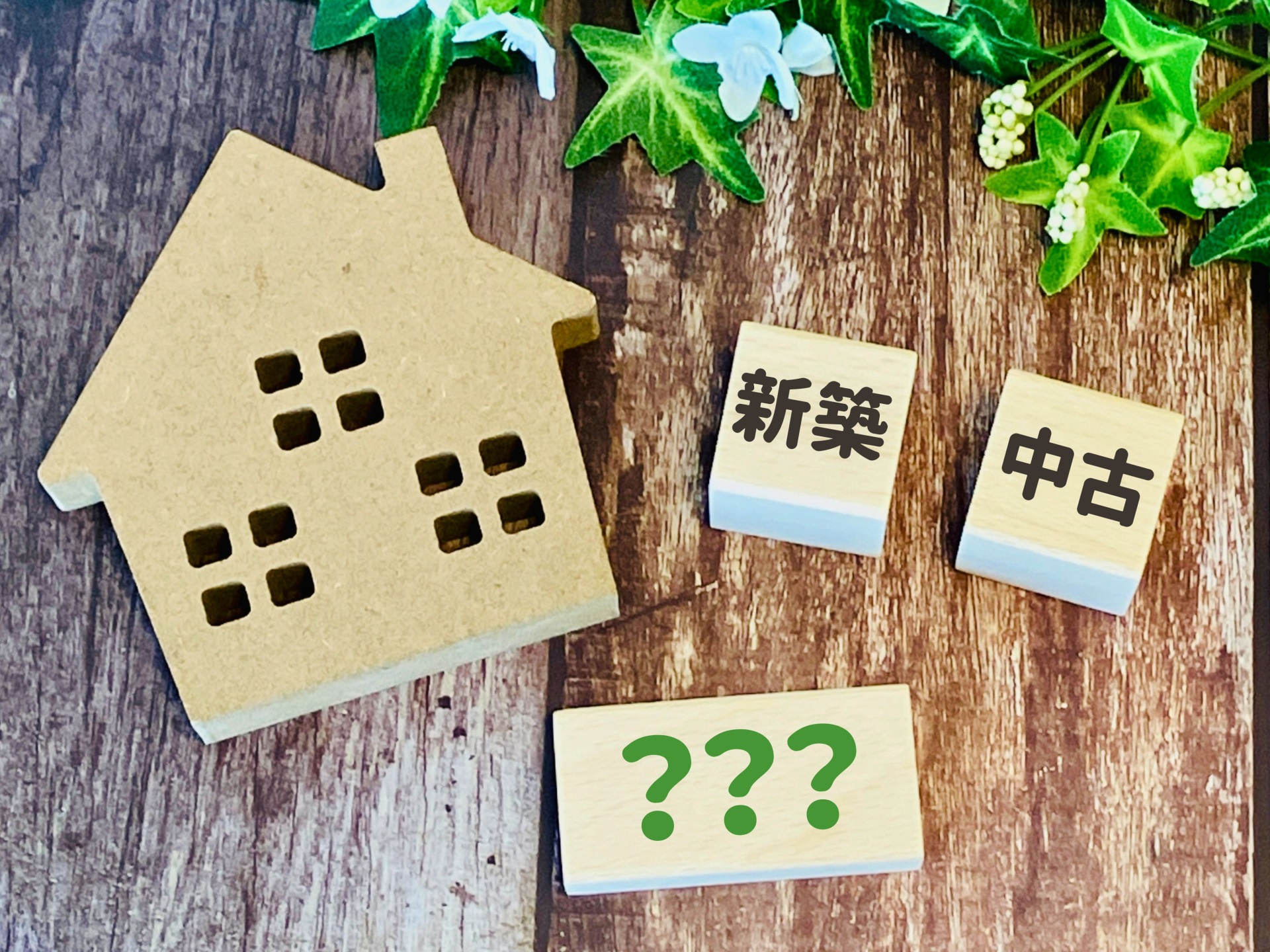 新築と中古の不動産投資を比較するイメージ画像。住宅模型と「新築」「中古」「？」の文字が並んでいる。